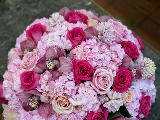 A floral arrangement featuring pink hydrangea, pink roses, hyacinth and orchid heads in a low cylinder vase. - Jerome Florists NYC