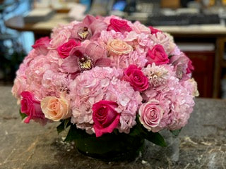 
                    
                      A floral arrangement featuring pink hydrangea, pink roses, hyacinth and orchid heads in a low cylinder vase. - Jerome Florists NYC
                    
                  