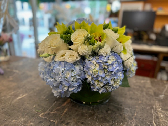 
                    
                      Blue hydrangea, green cymbidium orchids and hypericum berries, and white rose centerpiece – Jerome Florists NYC
                    
                  