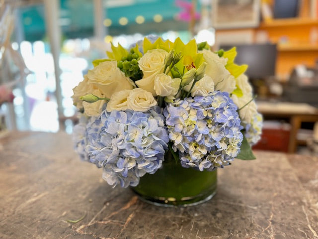 
                    
                      Blue hydrangea, green cymbidium orchids and hypericum berries, and white rose centerpiece – Jerome Florists NYC
                    
                  