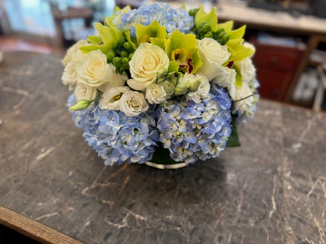 
                    
                       Blue hydrangea, green cymbidium orchids and hypericum berries, and white rose centerpiece – Jerome Florists NYC
                    
                  