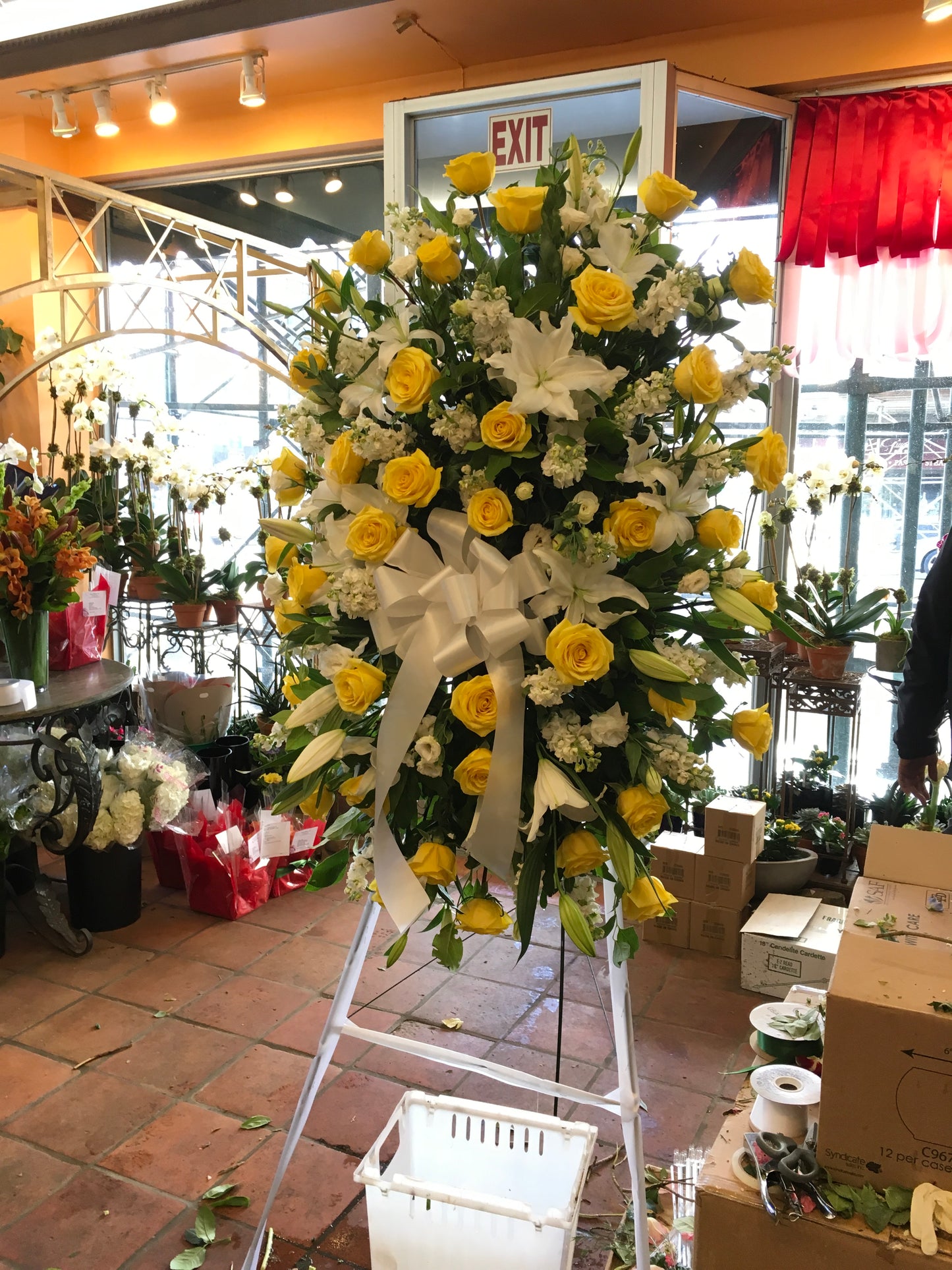Large sympathy spray with white roses and yellow lilies on an easel - Jerome Florists NYC