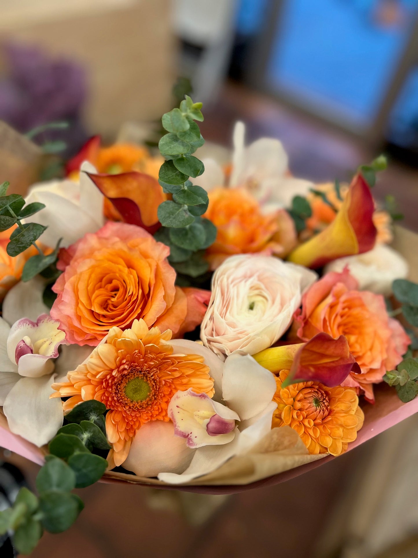 
                    
                      Orange pink roses, gerbera daisy, dahlias, cymbidium orchid heads, eucalyptus and ranunculus sunrise bouquet – Jerome Florists NYC
                    
                  