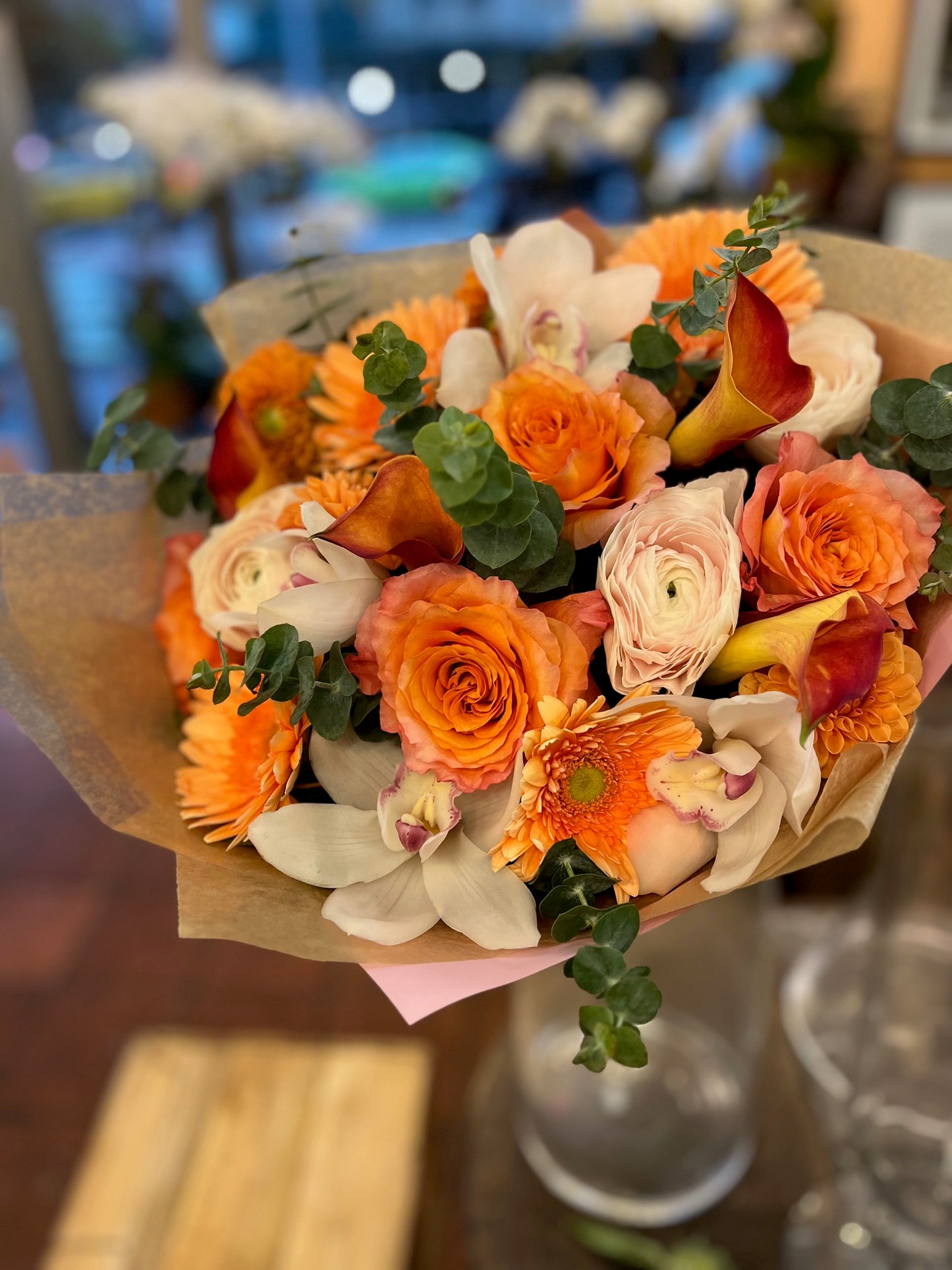 
                    
                      Orange pink roses, gerbera daisy, dahlias, cymbidium orchid heads, eucalyptus and ranunculus sunrise bouquet – Jerome Florists NYC
                    
                  