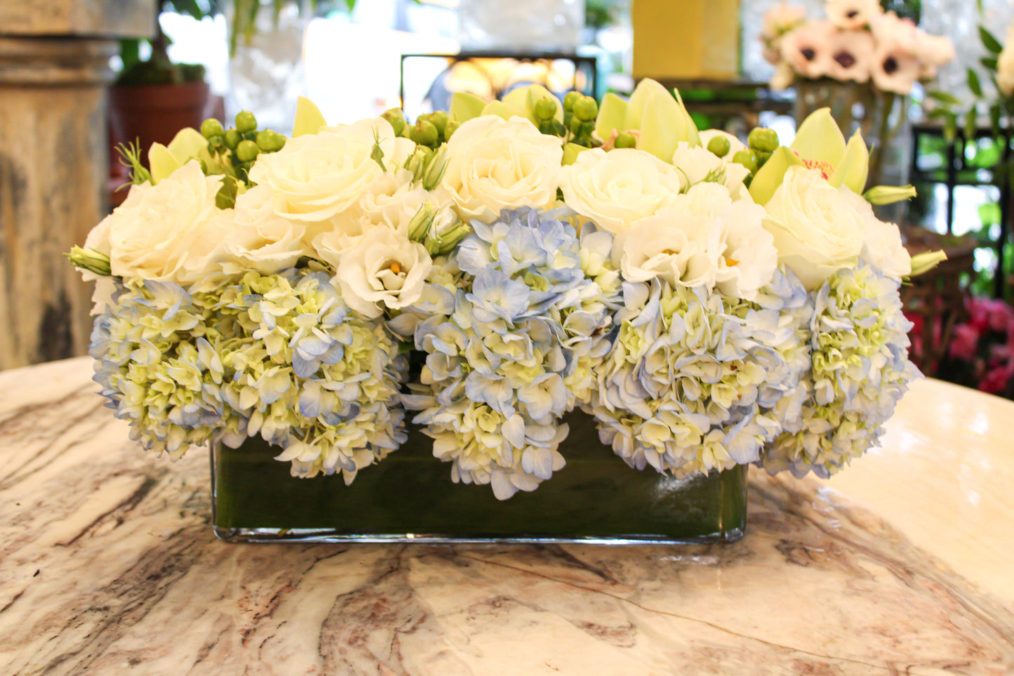 Blue hydrangea, green cymbidium orchids and hypericum berries, and white rose centerpiece – Jerome Florists NYC
