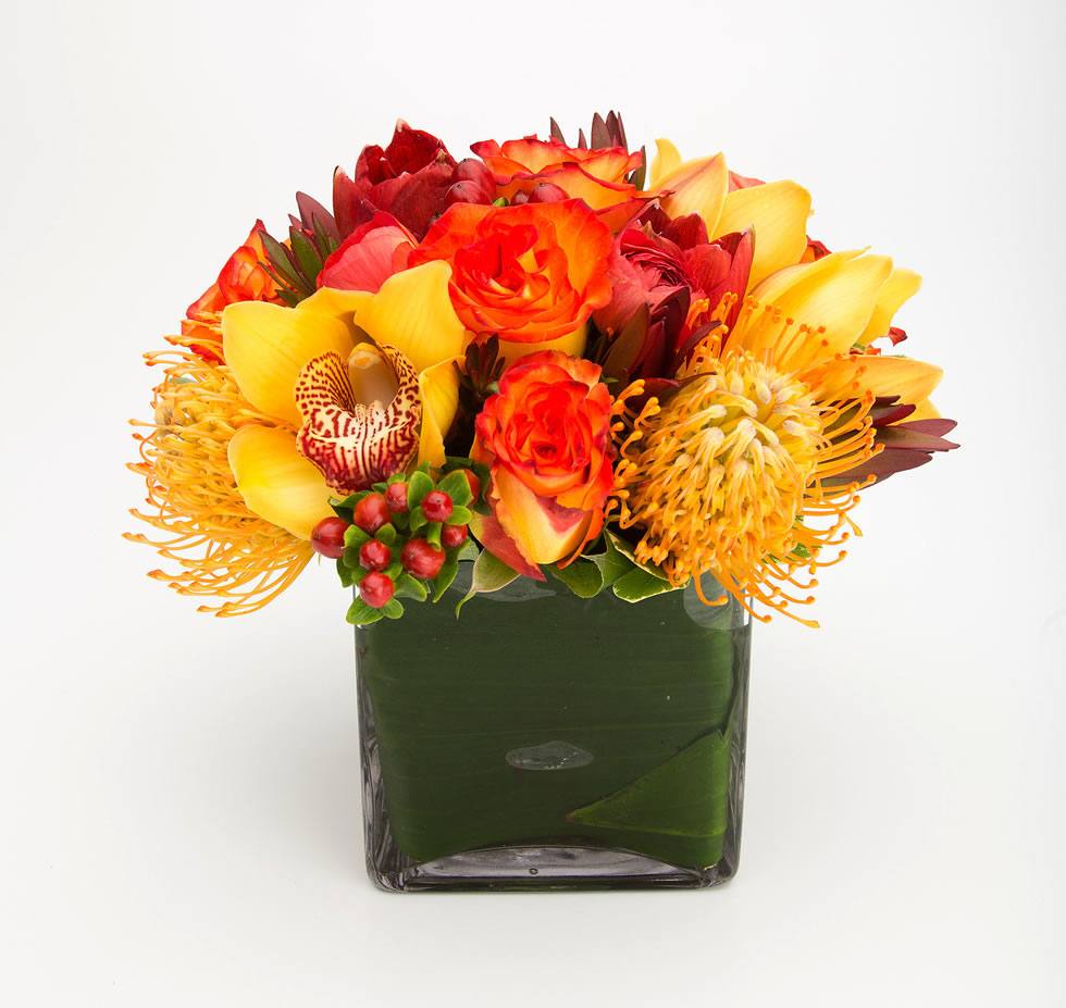 Exuberance - A Delightful Floral Cube Arrangement or yellow red roses, yellow cymbidium orchid heads, proteas and hypericum berries - Jerome Florists NYC